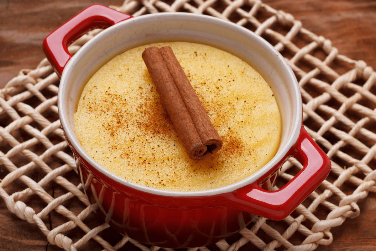 Brazilian sweet corn pudding in red dish with cinnamon stick