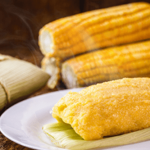 Brazilian pamonha on plate with fresh corn in the background