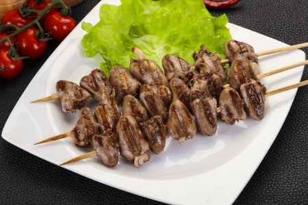 grilled chicken hearts on skewers over a piece of lettuce