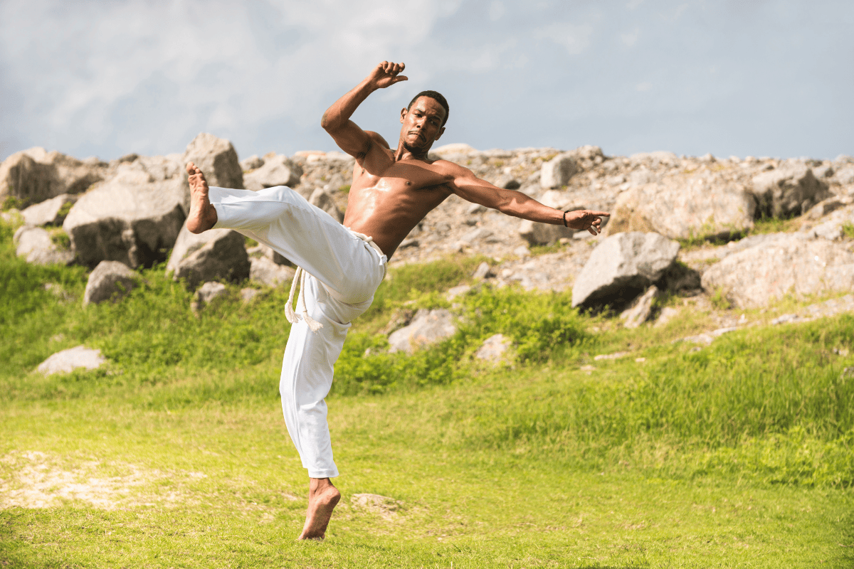 man practicing Capoeira in traditional white pants