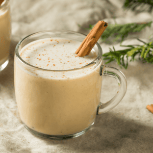 two glasses of eggnog garnished with cinnamon sticks