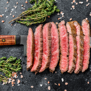 faldinha flap steak cooked rare and sliced with herbs and salt in the background