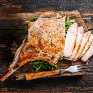 grilled tomahawk pork chop on a bed of arugula