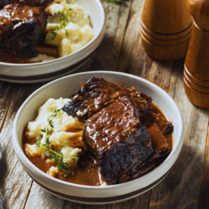 braised beef short ribs in bowls over mashed potatoes